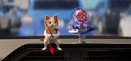 A toy cat and alien on a car dashboard