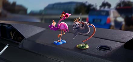 A toy sloth and flamingo on a car dashboard