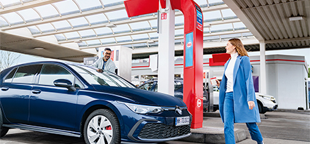 Two friends getting into a car at an Esso service station