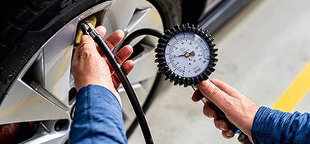 Image of a mechanic checking a tyre’s pressure