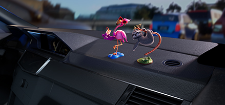 flamingo and sloth bobbleheads sat on a car dashboard