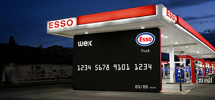 A zoomed in version of the Esso Card™ Truck with an Esso station behind it, at night