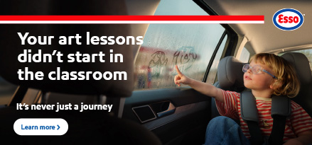 Child in a car seat drawing smiley faces on a fogged-up window.
